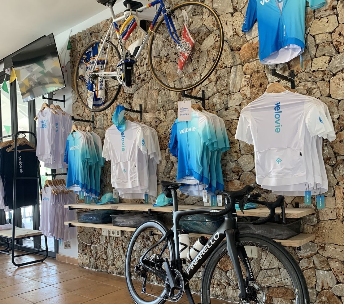 Retail display of cycling kit mounted on a stone wall with a bike